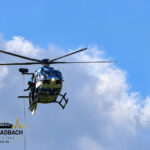 Polizeihubschrauber lässt einen Transportkorb für Einsatzmittel aus der Luft herab.